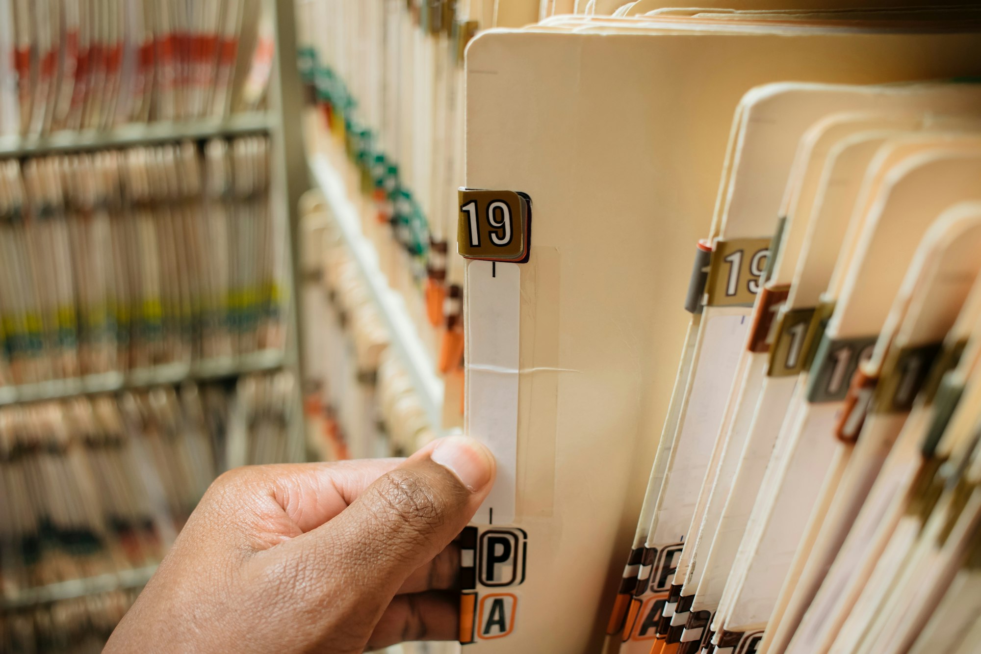 African American man pulling medical chart from pile of charts
