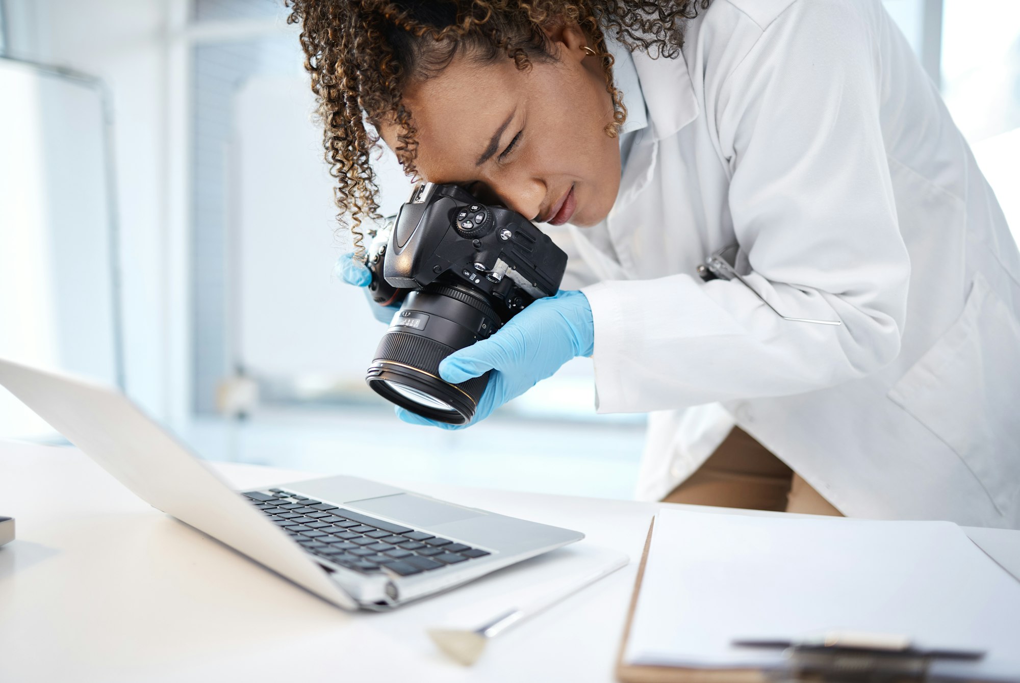 Black woman, forensic investigation and camera for laptop, it and cyber crime evidence on lab desk.