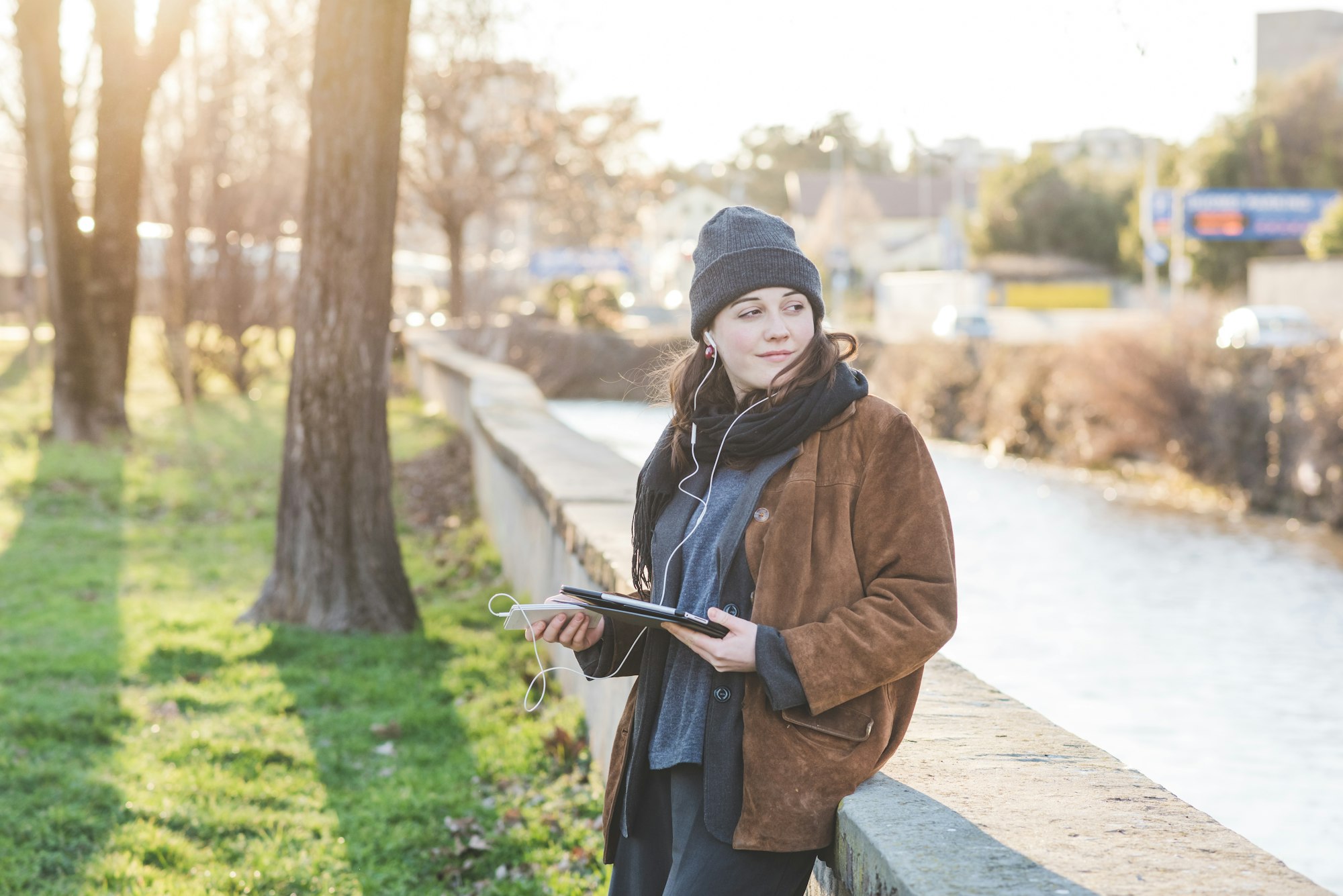 Young woman outdoor using tablet listening music